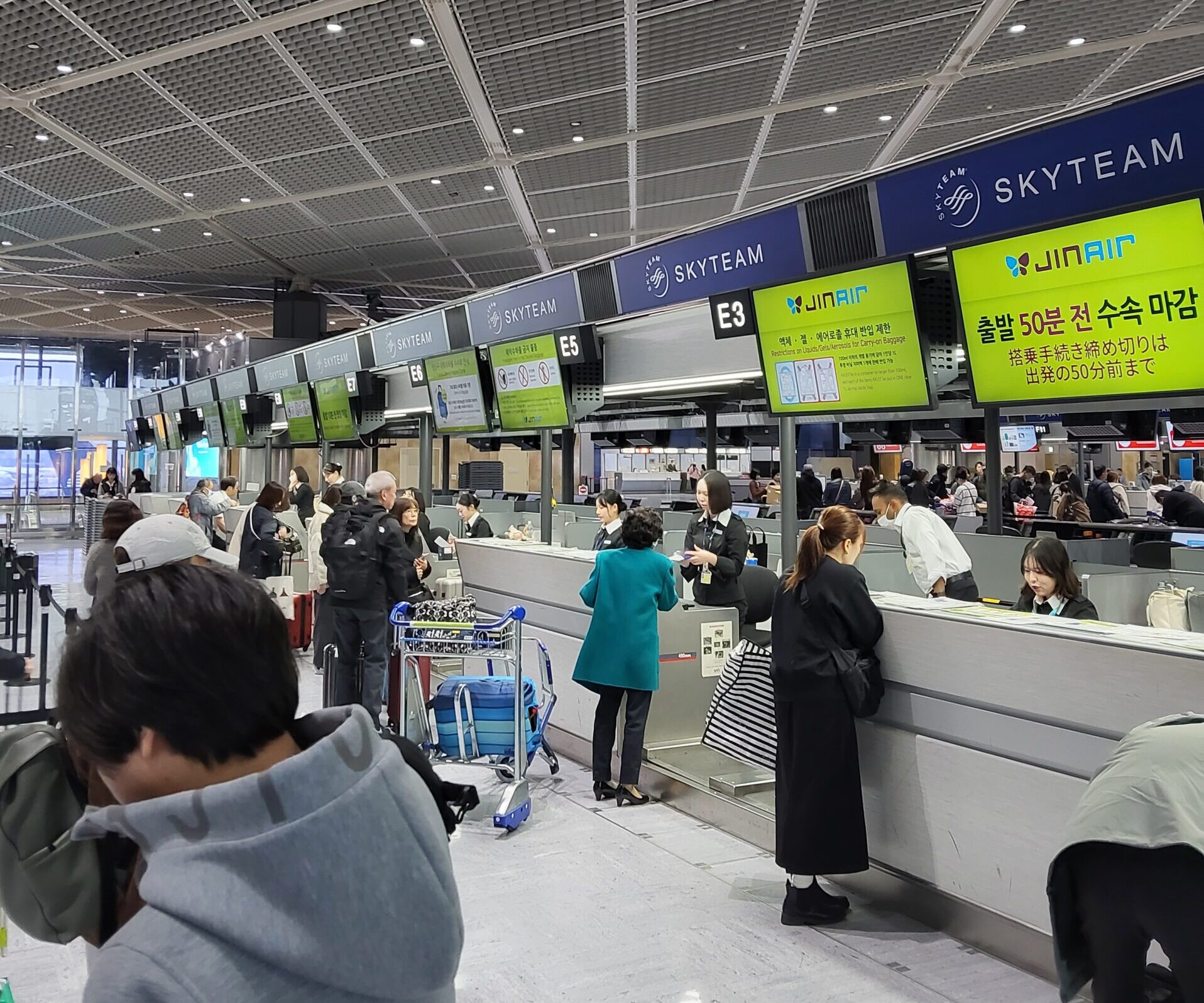 空港のジンエアーチェックインカウンターで搭乗手続きをする利用者