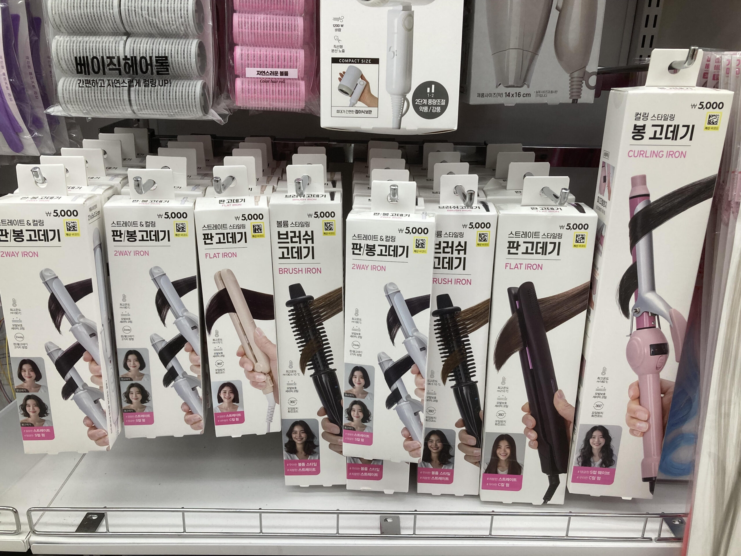韓国ダイソーのヘアアイロン売り場に並ぶ5,000ウォン表示のストレート・カール・ブラシ型の商品
